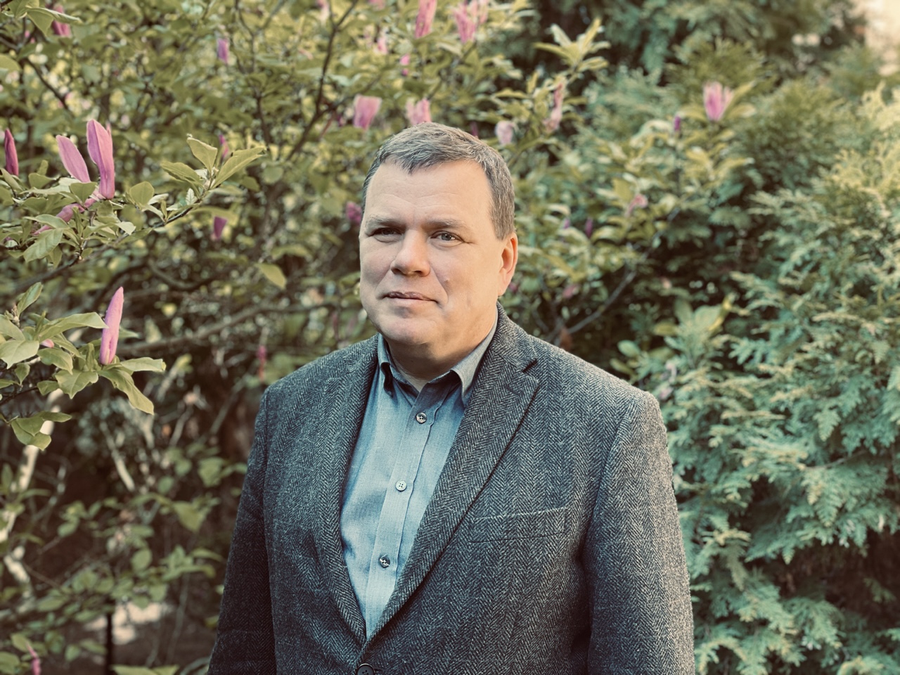 Tomasz Gwizdałła na tle zielonego krzewu
