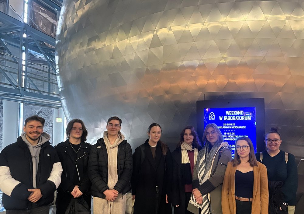 Na zdjęciu uczestnicy spotkania stojący przed kinem sferycznym. Zdjęcie przedstawia zarówno kobiety, jak i mężczyzn.