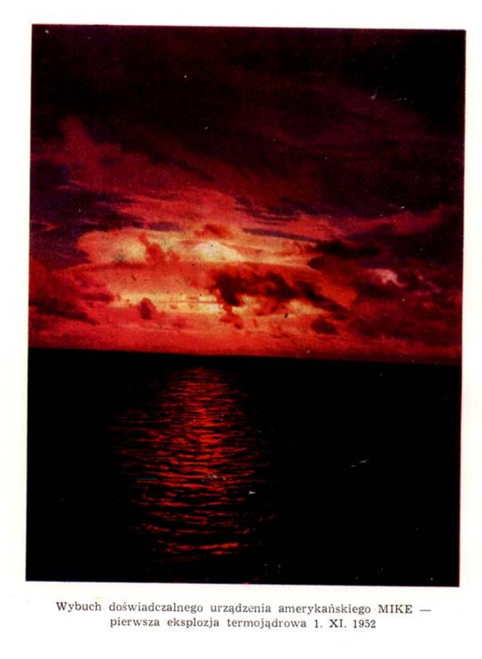 Na zdjęciu widoczny jest ciemny krajobraz morski oświetlony intensywną, czerwoną poświatą na niebie. Horyzont dzieli obraz na dwie części: górną z chmurami i dolną z powierzchnią wody. Niebo ma głęboki czerwony i pomarańczowy kolor, a chmury są nieregularne i miejscami bardzo jasne, jakby podświetlone od wewnątrz.  Na powierzchni morza widać odbicie czerwonego światła, które tworzy pionowy pas świetlny na falującej wodzie. Reszta wody pozostaje prawie czarna. Cała scena jest silnie kontrastowa i ma dramatyczny charakter.  Pod zdjęciem znajduje się podpis informujący, że fotografia przedstawia wybuch doświadczalnego amerykańskiego urządzenia o nazwie „Mike” – pierwszą eksplozję termojądrową, która miała miejsce 1 listopada 1952 roku.