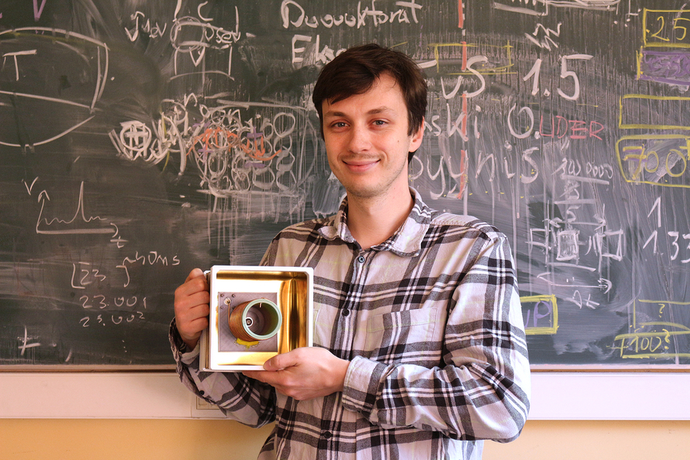 Maciej Ślot with a sensor against the background of a board with patterns written on it