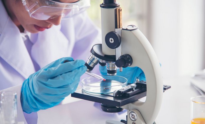 Woman scientist in lab look at science microscope medical test a Naukowczyni przeprowadzająca badania